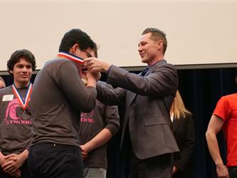Aaron Palm awarding medal to student